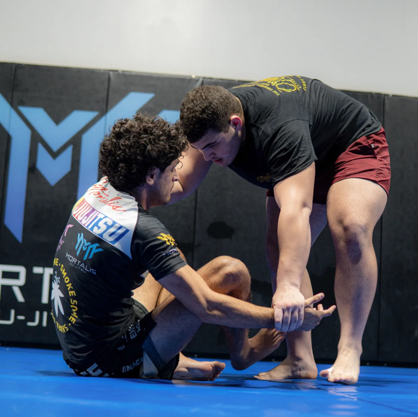 Two athletes drilling a leg entry on the Mortalis mat